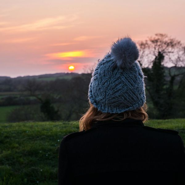 Person meditating peacefully outdoors during sunrise, with soft golden light.